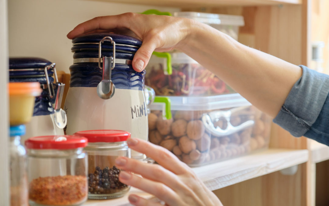 two hands on storage containers in a kitchen pantry